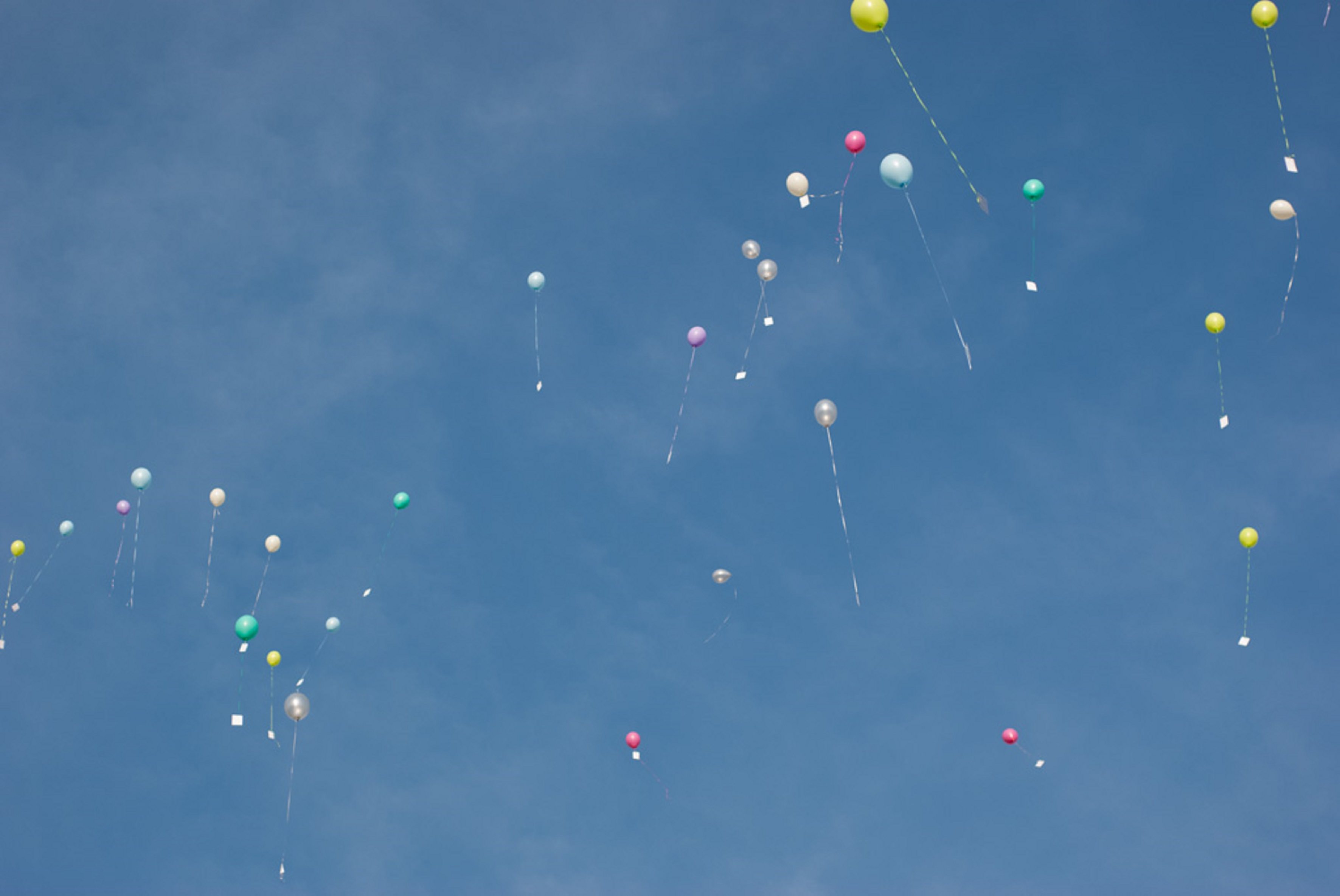 Kontakt. Blauer Himmel mit bunten Luftballons and denen Postkarten davonfliegen.